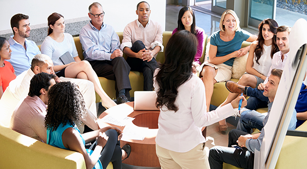 Image of a group of people sitting together in a circle holding a meeting