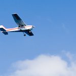 Image of an aeroplane in the air flying past white clouds on a clear sunny day
