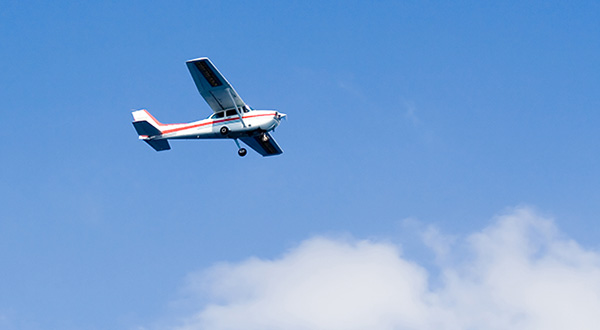 Image of an aeroplane in the air flying past white clouds on a clear sunny day