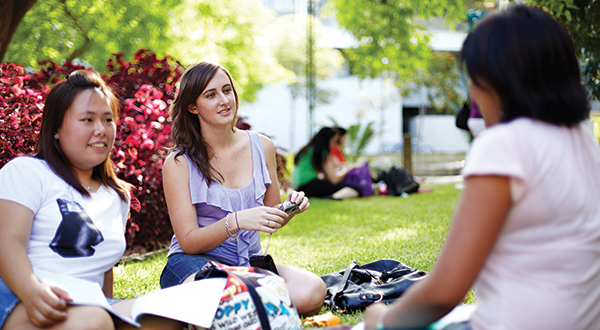 Image of university students sitting on lawn and talking